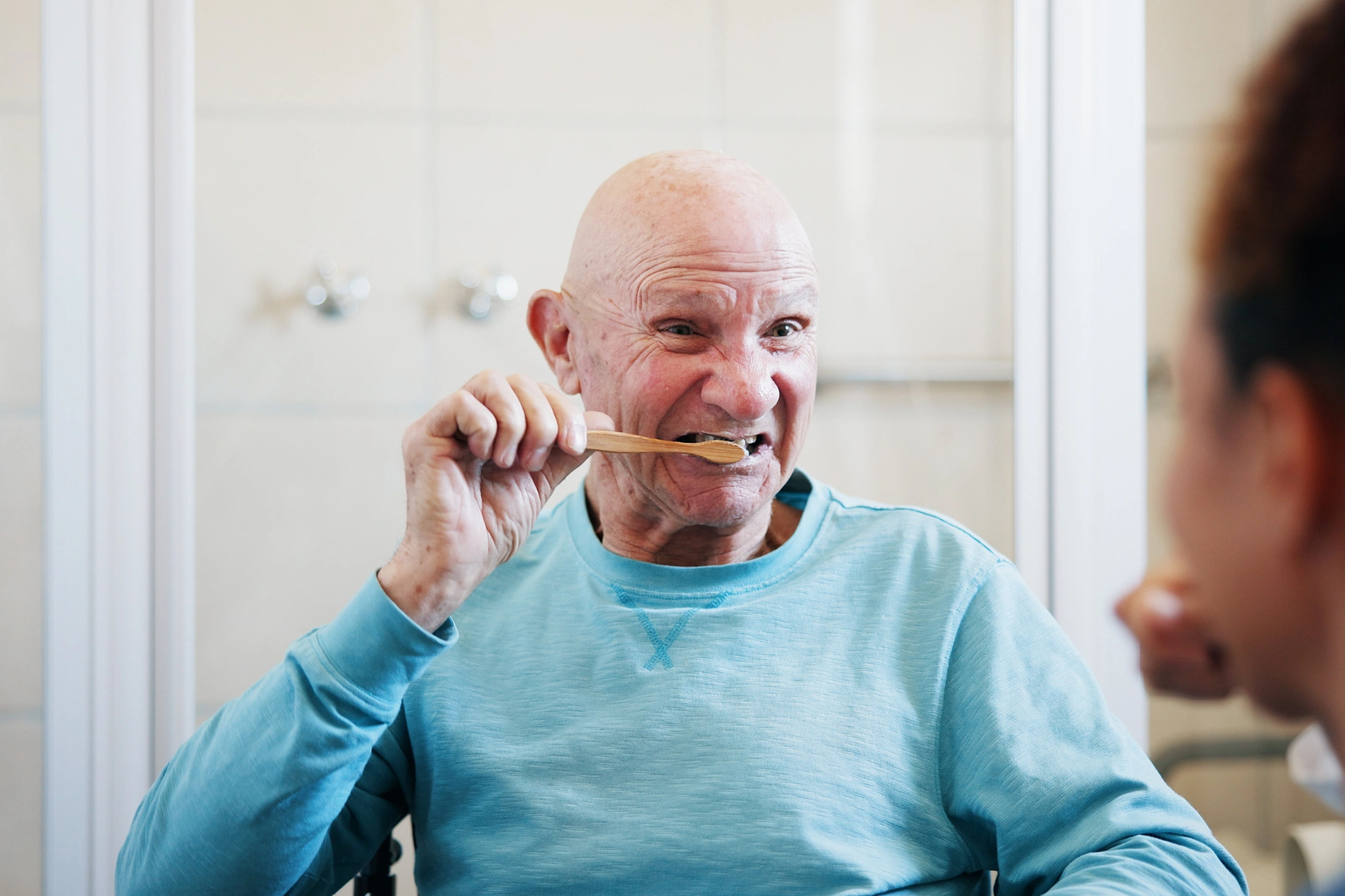 Senior man, nurse and help for brushing teeth in bathroom, motor skills exercise and dental hygiene